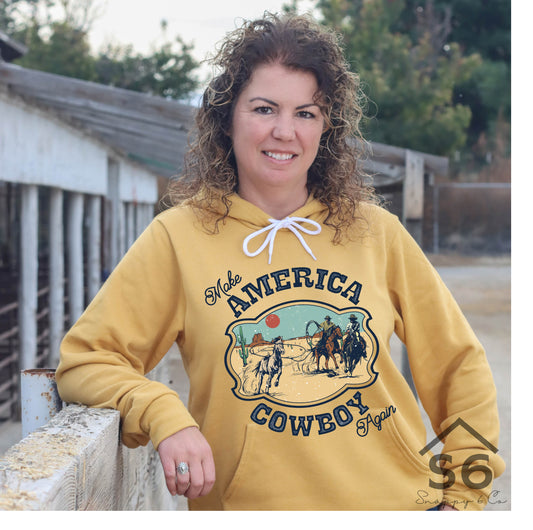 Michelle From Snappy 6 Co Leaning against a fence in a gold sweatshirt decorated with a colorful western transfer from Snappy 6 Co